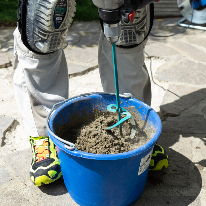 Steinkleber mit elektrischen Rührgerät im Mörteleimer anrühren.