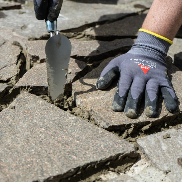 Überschüssigen, frischen Steinkleber aus den Fugen der Polygonalplatten mit einer Fugenkelle oder Katzenzunge entfernen..