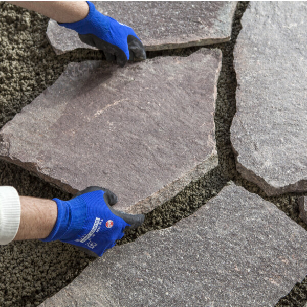 Polygonalplatten werden passend auf dem frischen Pflasterdrainmörtel verlegt.