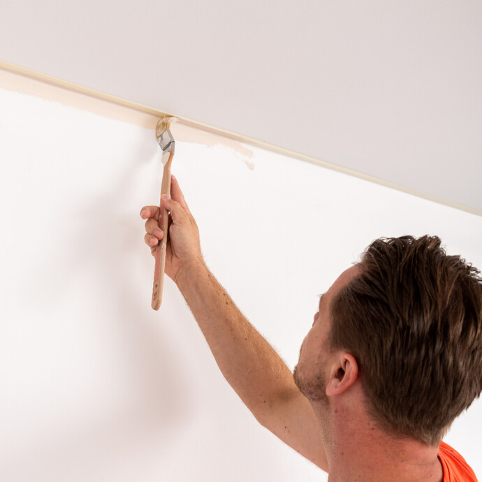 Am Übergang von Wand und Decke Wandfarbe mit dem Pinsel vorstreichen