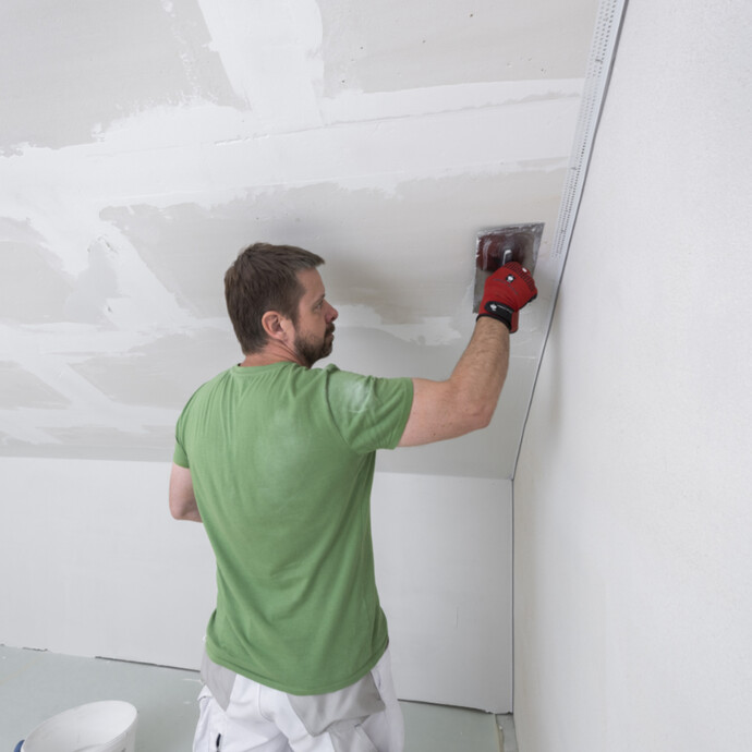 weiße Spachtelmasse flächig mit einer Glättkelle an der Wand und der Dachschräge auftragen