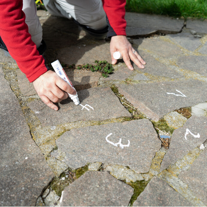 Lose Polygonalplatten auf der Terrasse für den späteren Wiedereinbau markieren.