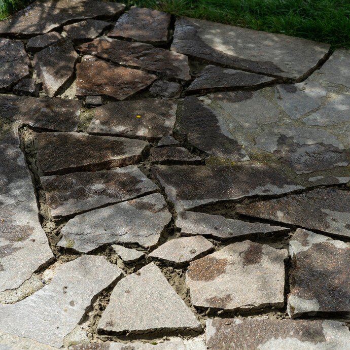 Fertig verlegte Polygonalplatten bei der Reparatur von losen Natursteinplatten.