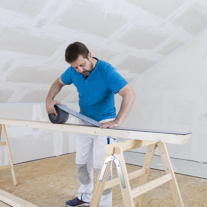 selbstklebendes Dichtband auf die Unterseite des Rahmenholzes der Holzständerwand aufkleben